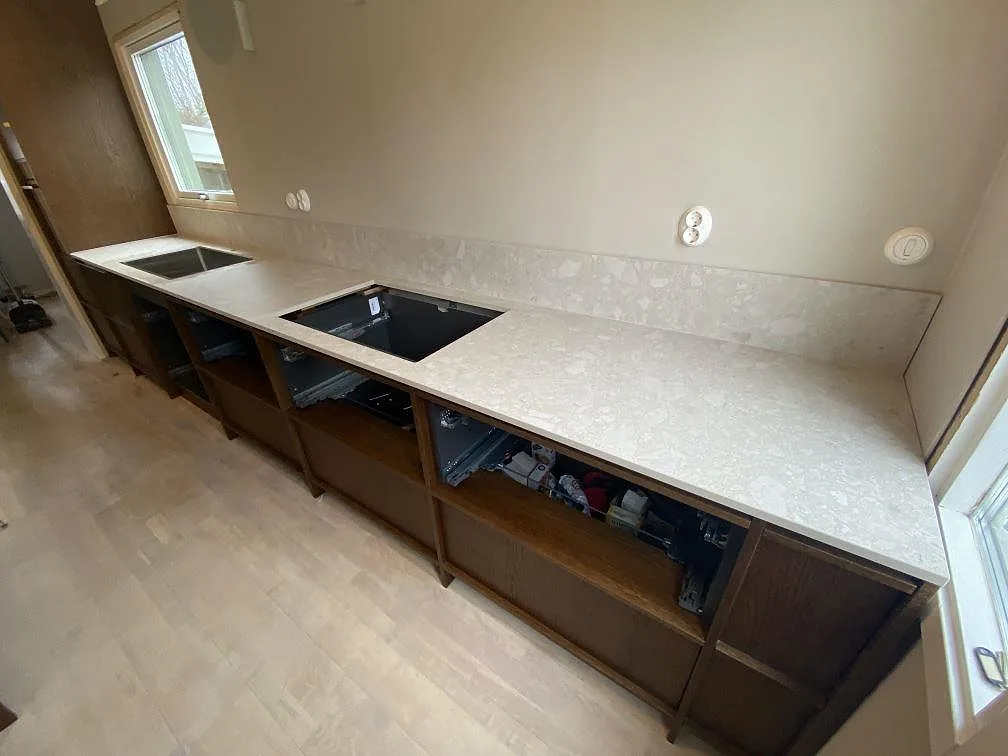 Køkkenbordplade i mat Dekton Ava, lys keramik med låg stänkkant, rostfri vask og hällöppning i ett køkken i Göteborg.