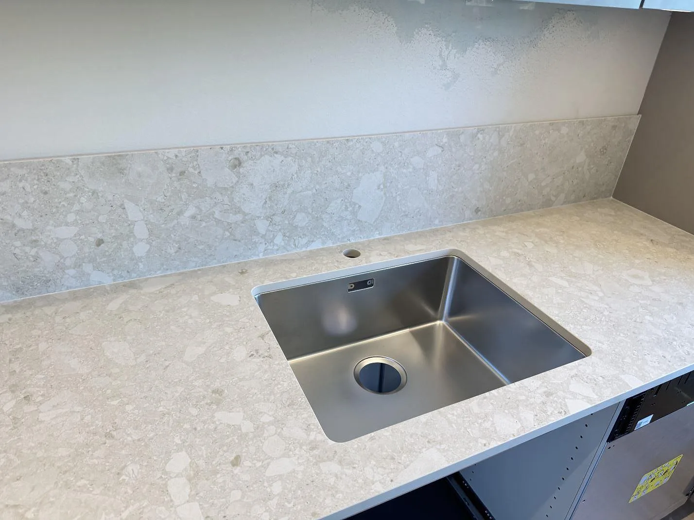 Køkkenbordplade i mat Dekton Ava, keramik, med rostfri vask og matchande stænkplade i ett køkken i Mölndal.