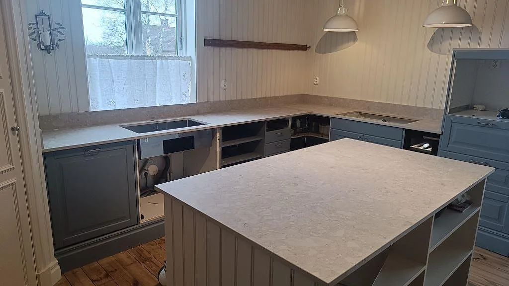 Køkkenbordplade og køkkenø i mat Dekton Ava, keramik, med uppvikt stänkkant i ett køkken i Nässjö.