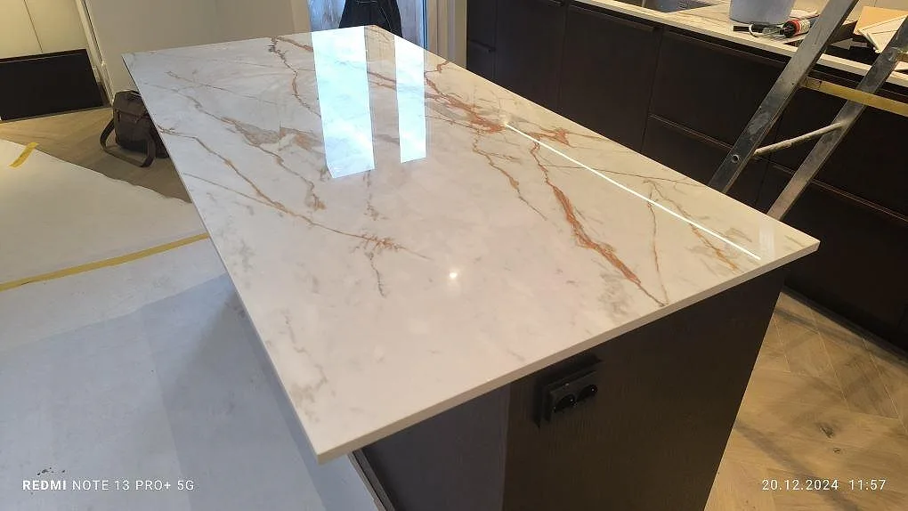 Køkkenø med Bordplade i hvid marmorerad Dekton Awake, poleret keramik i 20 mm, under montering i ett køkken i Stockholm.