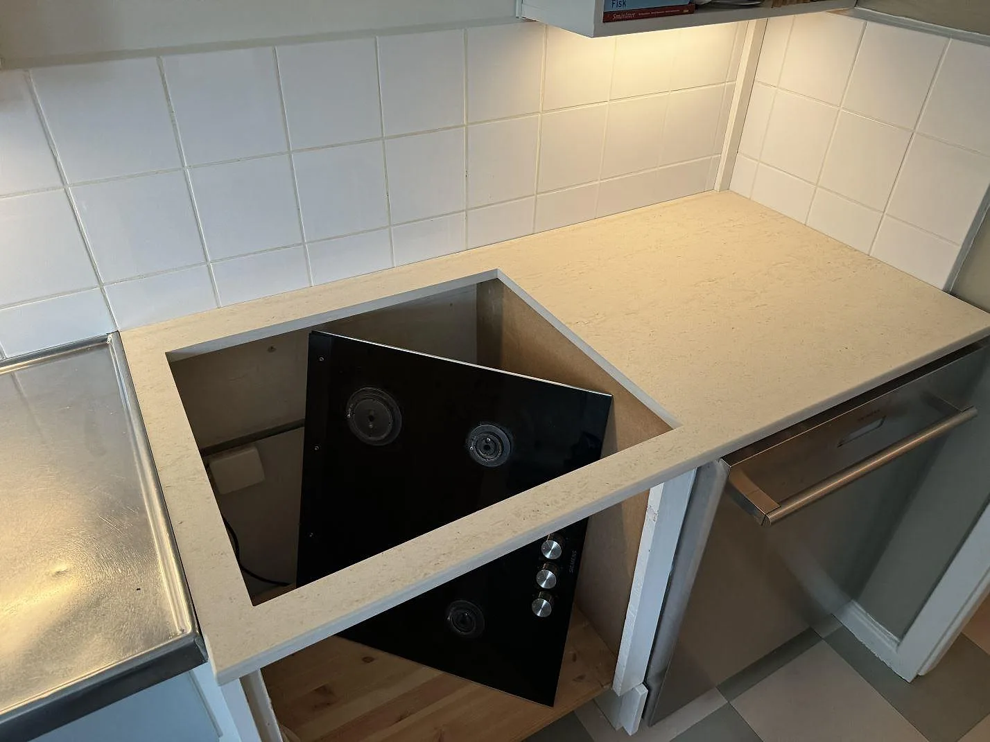 Køkkenbordplade i mat Dekton Danae, keramik, med hälluttag og lös kogeplade under montering i Malmö.