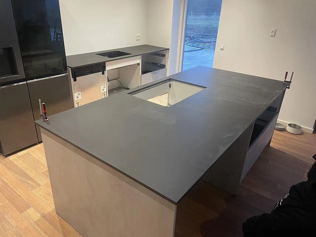 Køkkenbordplade i mat Dekton Domoos med køkkenø og lige bänkrad under montering i Haslev.