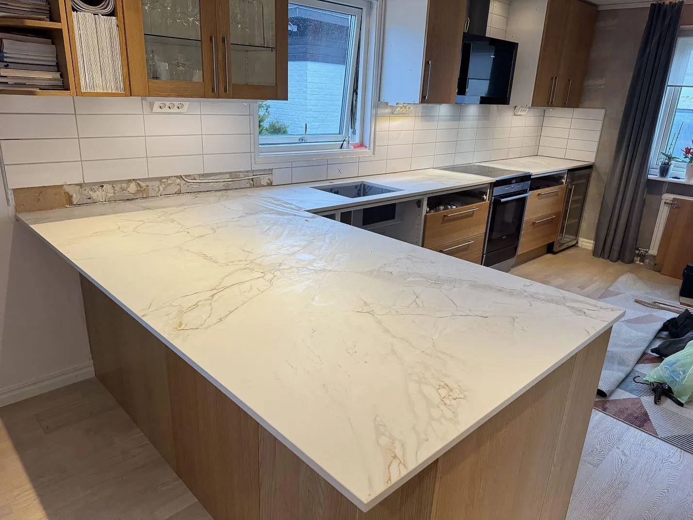 Køkkenbordplade og køkkenø i 20 mm mat Dekton Entzo, hvid keramisk sten med grå åretegning i ett køkken i Sätila.