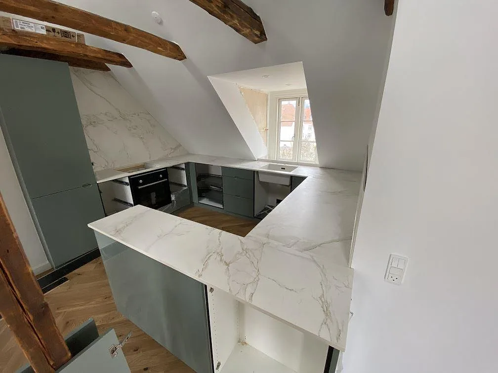 Køkkenbordplade i keramik, mat Dekton Entzo med lys åretegning og U-formad arbetsyta i ett køkken i Valby.