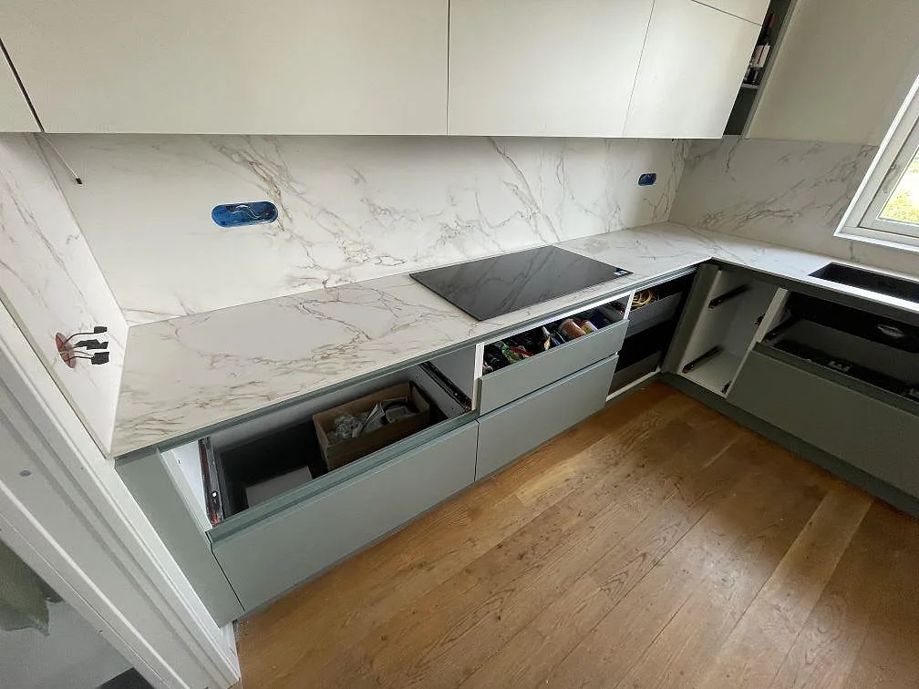 Køkkenbordplade i mat Dekton Entzo keramik med matchande vægbeklædning og mørk hällzon i ett køkken i Vendelsö.