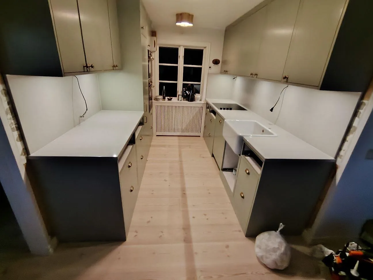 Køkkenbordplader i mat Dekton Kovik keramik längs båda väggarna i ett parallellkök under montering i Arholma.