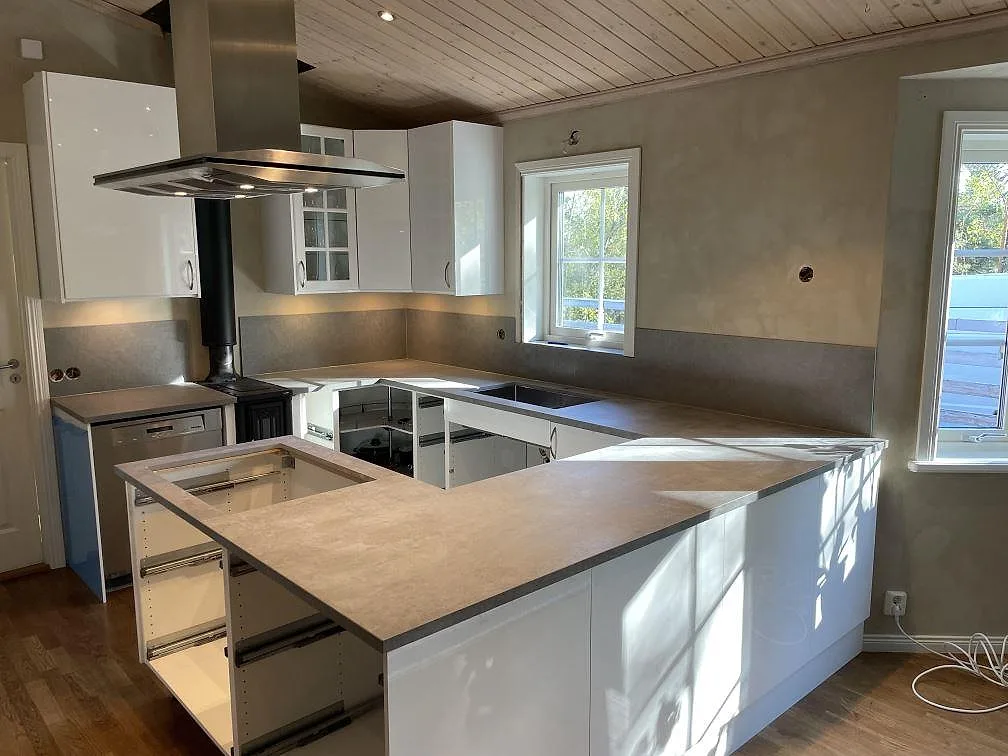 Køkkenbordplade i mat Dekton Kreta med matchande stænkplade og framskjuten bänkdel i ett køkken i Vendelsö.