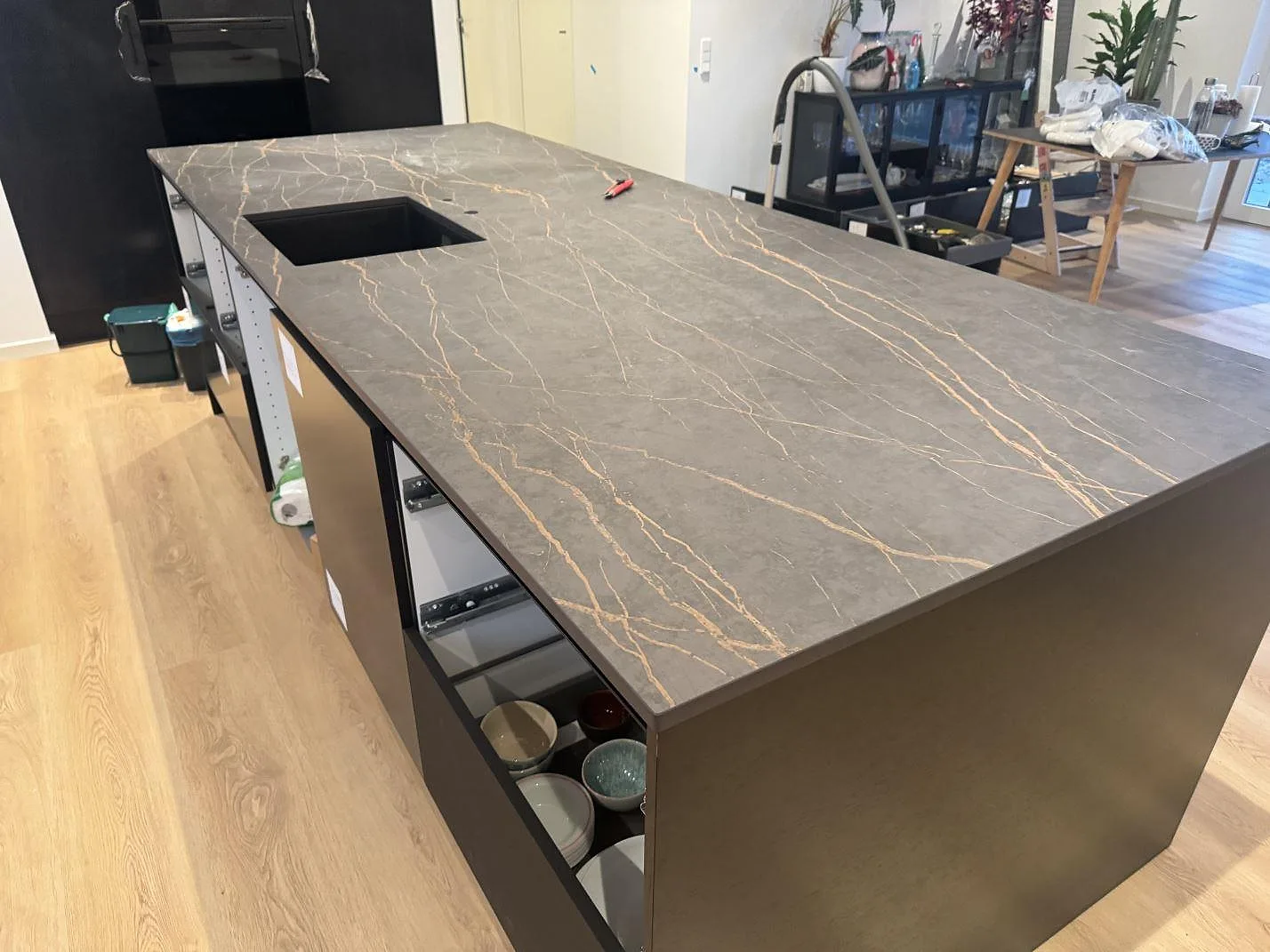 Køkkenø med Bordplade i 20 mm mat Dekton Laurent, mørk keramik med varm guldådring, under montering i ett køkken i Odense SV.