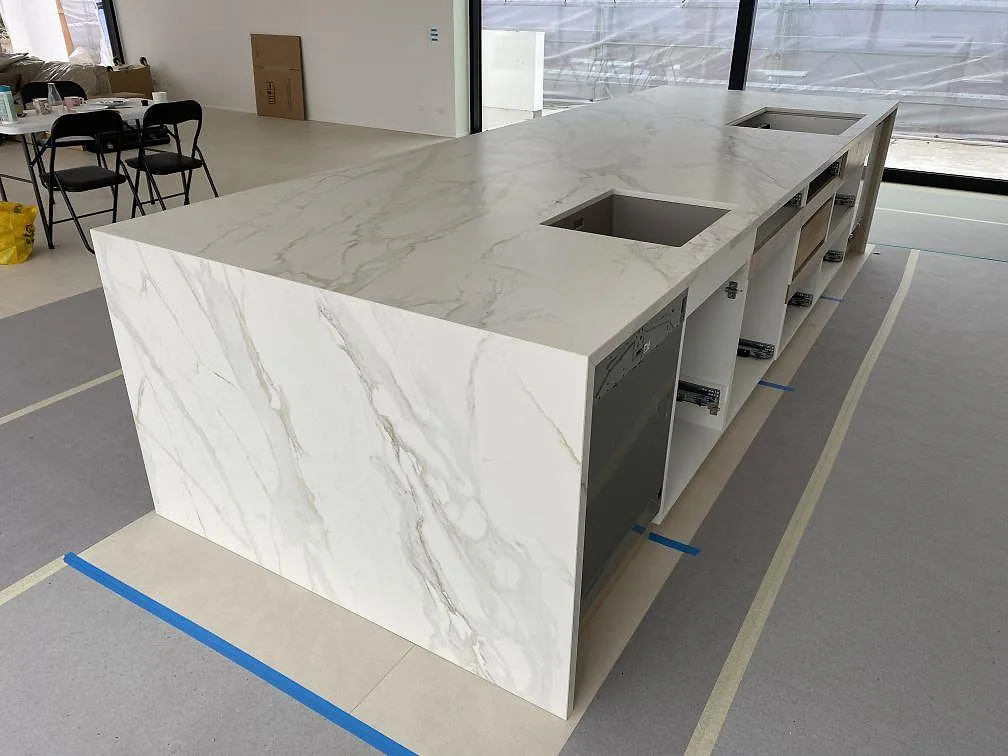 Køkkenø og køkkenbordplade i mat Dekton Neural med grå åretegning og neddragna gavlar i ett køkken i Ålsgårde.