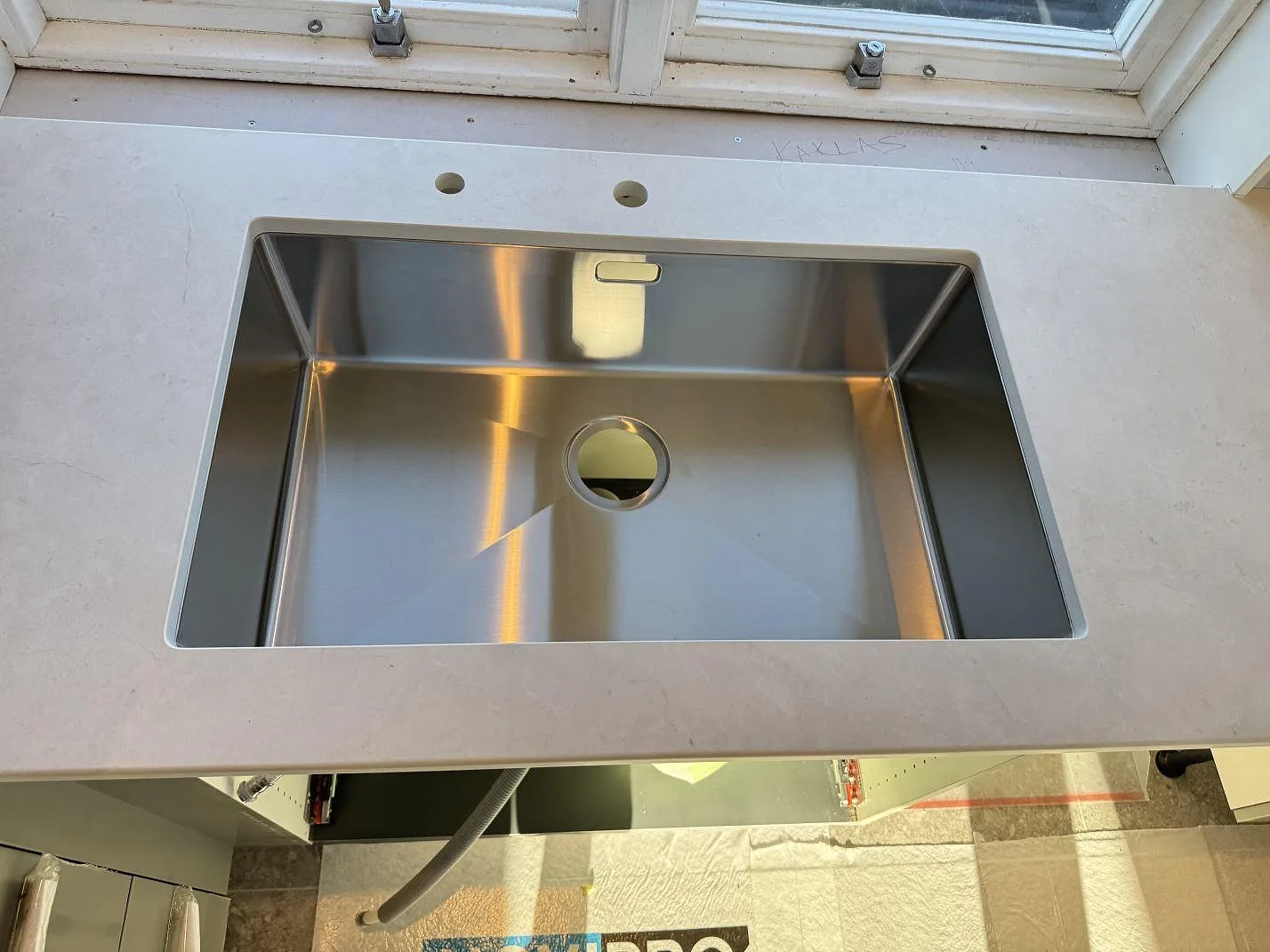 Køkkenbordplade i mat Dekton Sandik, lys keramik, med vask og Armaturhul foran vindue i Malmö.