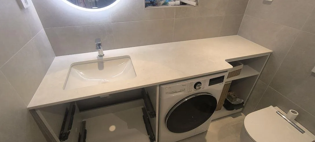 Badrumsbänkskiva i mat Dekton Sandik med tvättställ og tvättmaskin i ett Badeværelse i Värmdö.