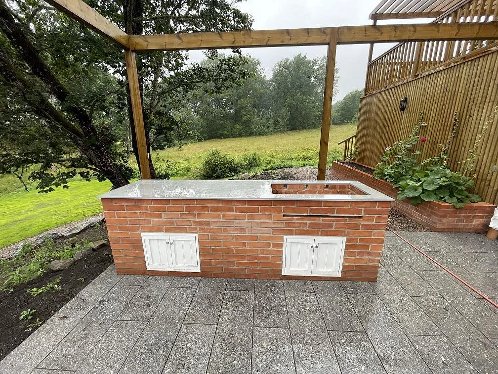 Bordplade i mat Dekton Soke, keramik, monteret i ett udekøkken på tegelunderrede under pergola i Flen.
