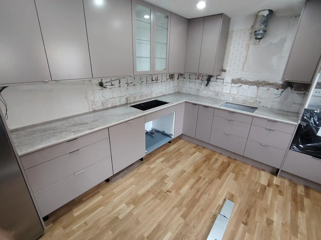 L-formad køkkenbordplade i poleret Dekton Taga, 20 mm keramik, med sort vask og rektangulärt udskæring under montering i Norsborg.
