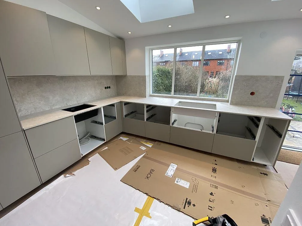 Køkkenbordplade i mat Dekton Tk05 Sabbia, keramik, med matchande stænkplade og öppna köksstommar under montering i Malmö.