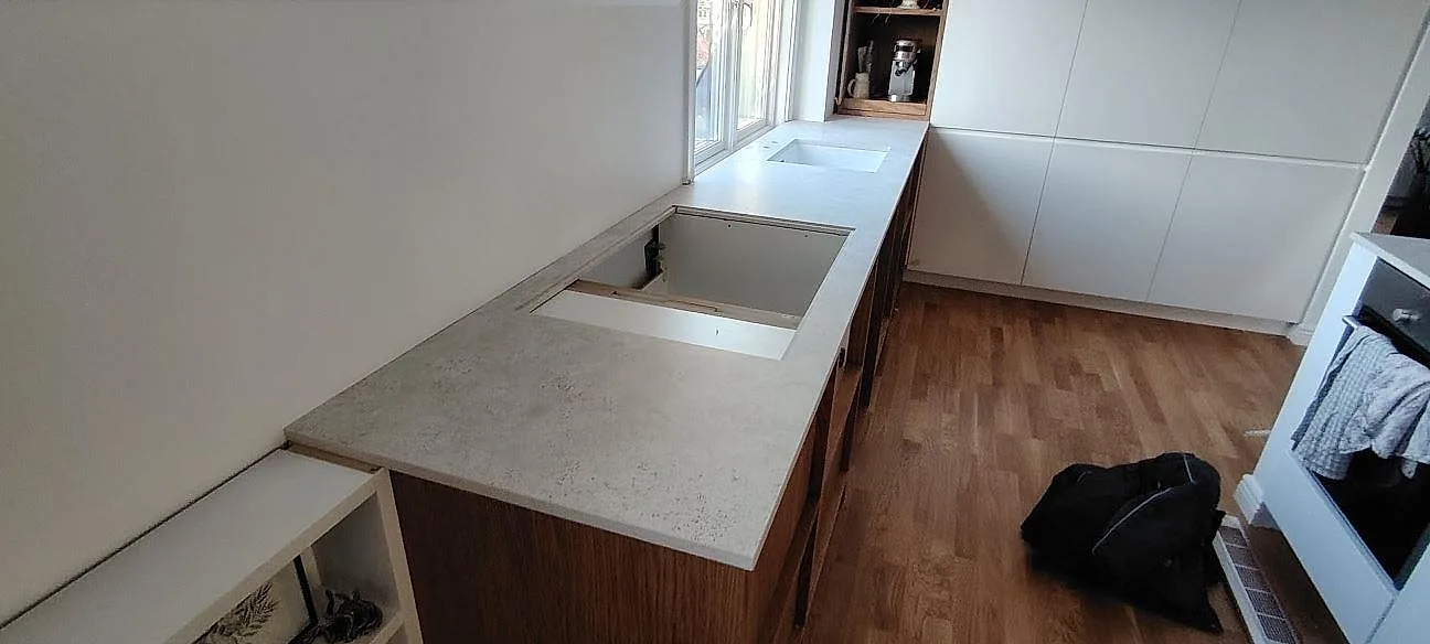 Køkkenbordplade i mat Dekton TK05 Sabbia, keramik, med synliga udskæring i ett køkken i Nacka under montering.