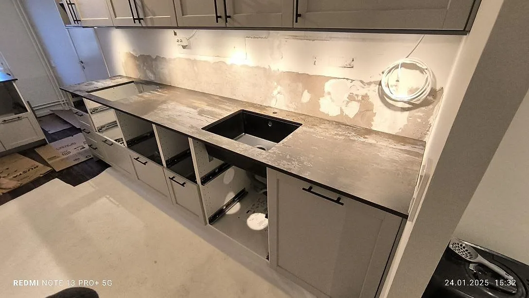 Køkkenbordplade i mat Dekton Trilium, keramik, med vask og väggnära bänksträcka under montering i Solna.