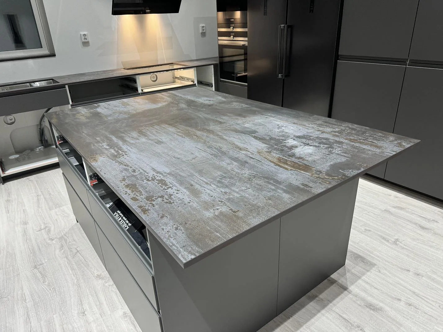 Stor køkkenø i mat Dekton Trilium med metallisk keramikyta i ett grått køkken i Torslanda.