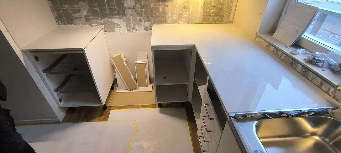 Køkkenbordplade i lys poleret Dekton Tundra 19 med vask under montering i ett køkken i Stockholm.
