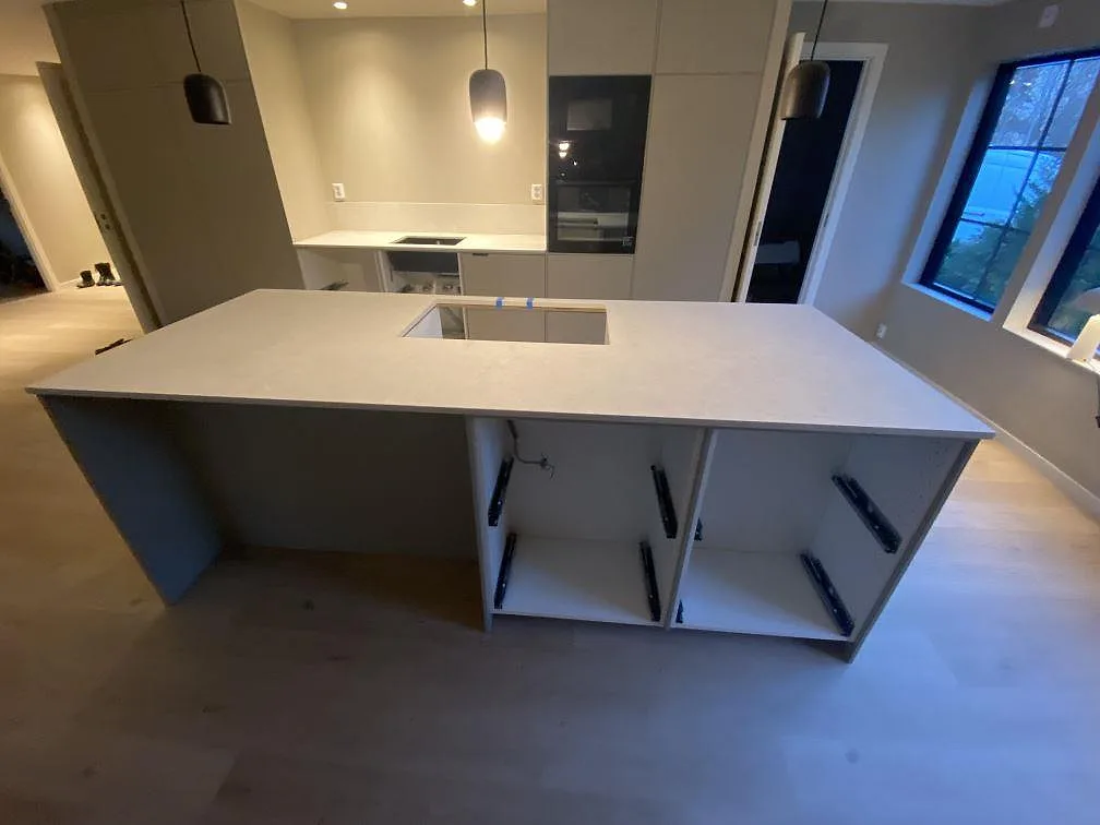 Køkkenbordplade og køkkenø i mat Dekton VK01 Nebbia, lys keramik, under montering i ett køkken i Älmhult.