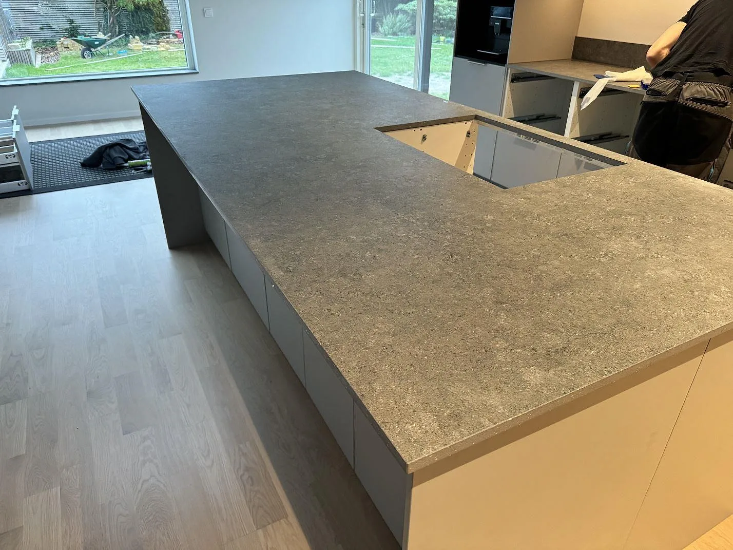 Køkkenø og køkkenbordplade i mat Dekton Vk04 Grafite med stor arbetsyta og öppning i ett køkken i Lomma.