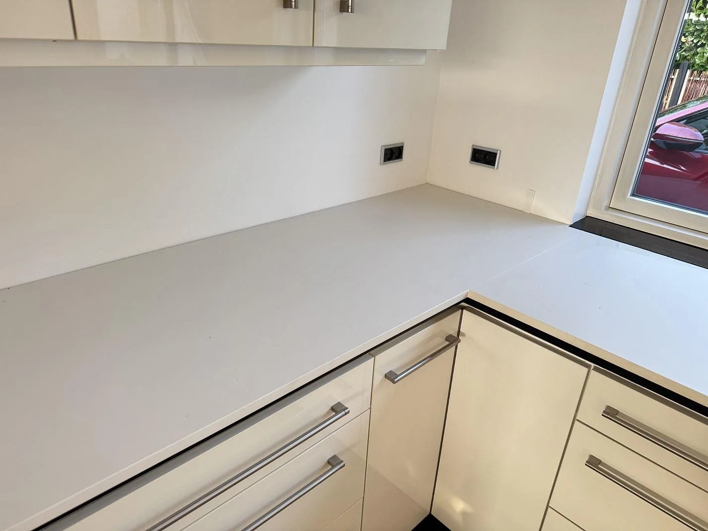 Køkkenbordplade i hvid Dekton Zenith, mat keramik, med L-formad arbetsyta og fönsterläge i ett køkken i Stenløse.