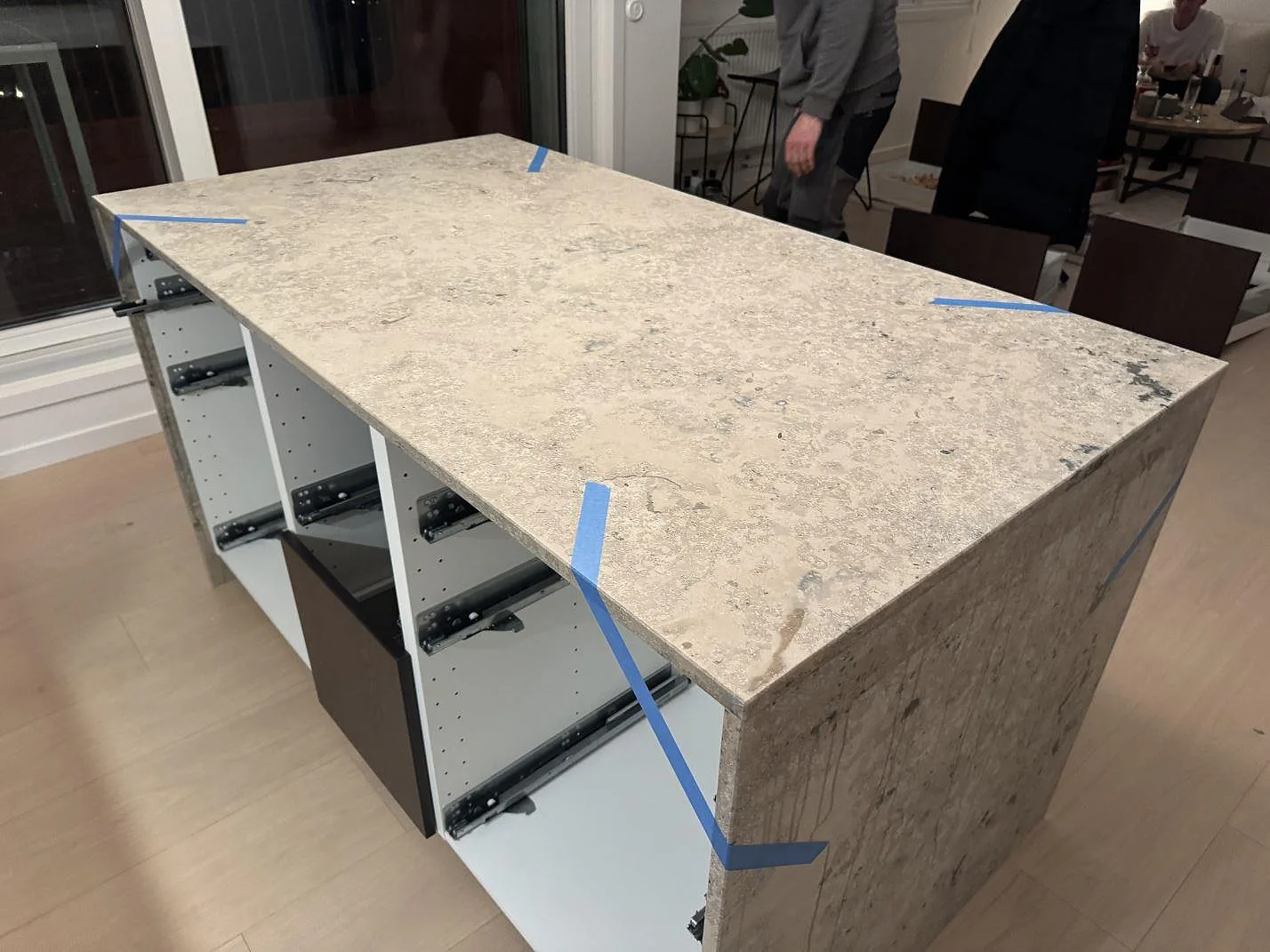 Køkkenbordplade i mat Jura Grey, 20 mm, på køkkenø med neddragna stensidor i ett køkken i Göteborg.