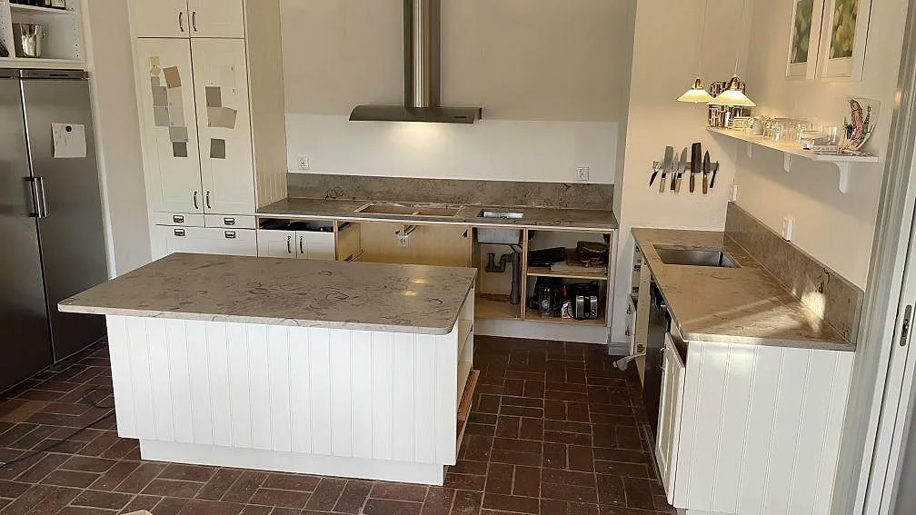 Køkken i Helsingborg med mat Jura Grey kalksten som køkkenbordplade, køkkenø og stænkplade under köksfläkten.