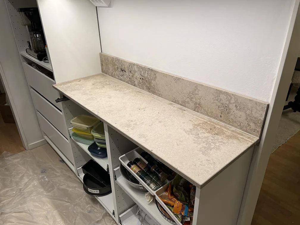 Køkkenbordplade i mat 20 mm Jura Grey kalksten med uppvikt stænkplade på vita köksstommar i Johanneshov.