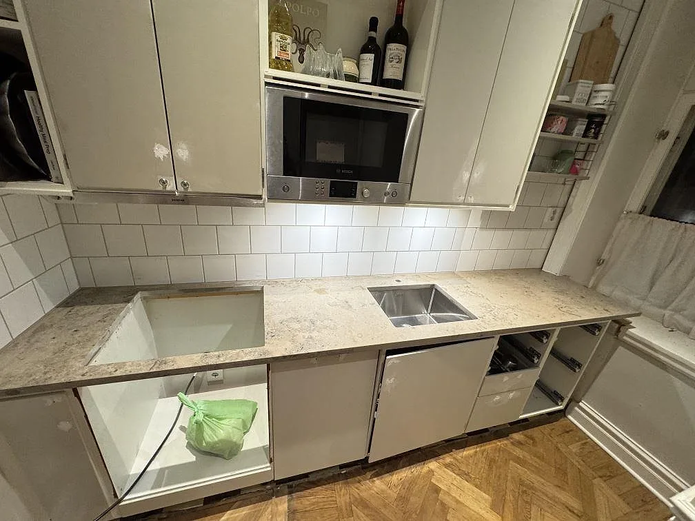 Køkkenbordplade i mat Jura Grey kalksten, 30 mm, monteret som lang väggbänk med diskhoområde og kaklad væg i ett køkken i Lund.