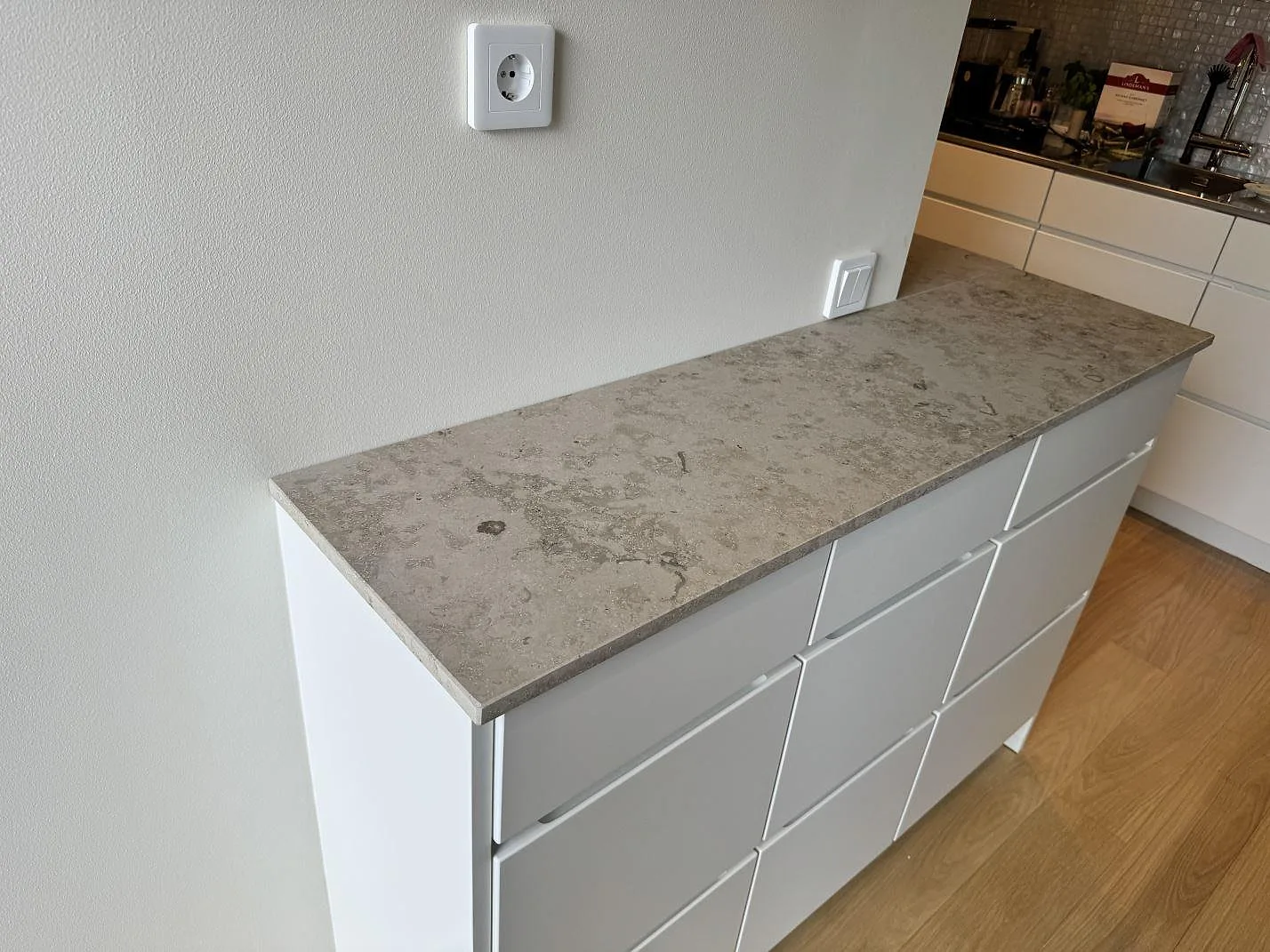 Køkkenbordplade i mat Jura Grey kalksten på hvid skåprad mot lys væg i Malmö.