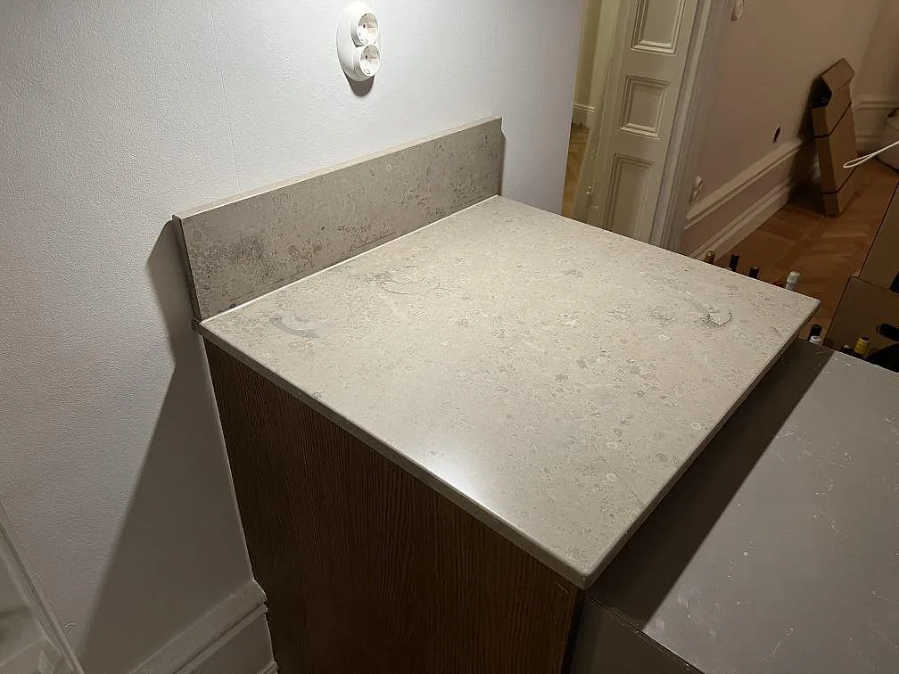 Mat køkkenbordplade i Jura Grey kalksten, 20 mm, med låg stänkkant og fossilrik overflade i ett køkken i Stockholm.