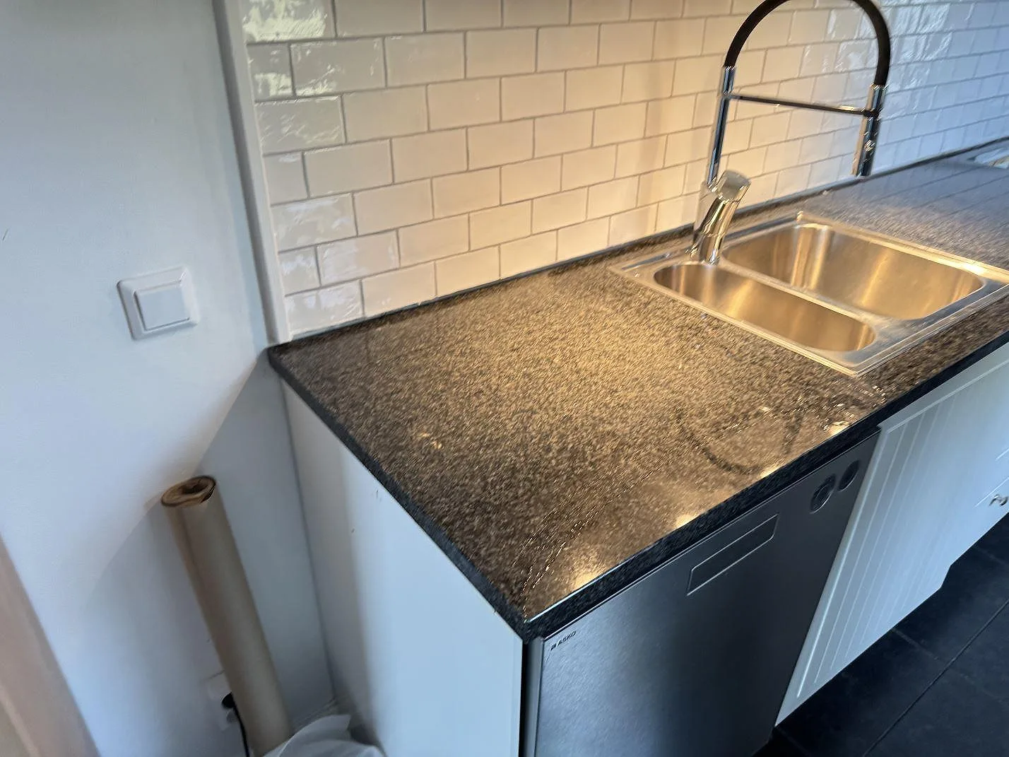 Køkkenbordplade i poleret Nero Africa granit med rostfri dubbelho og sort køkkenarmatur i Göteborg.