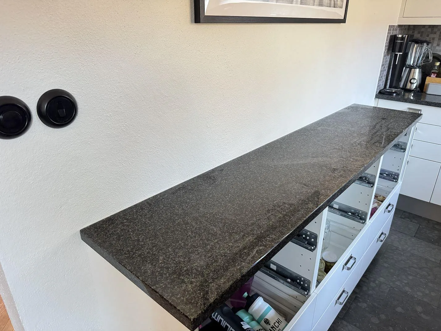 Køkkenbordplade i 30 mm poleret Nero Africa granit på hvid köksförvaring i Malmö, fotograferad under montering.