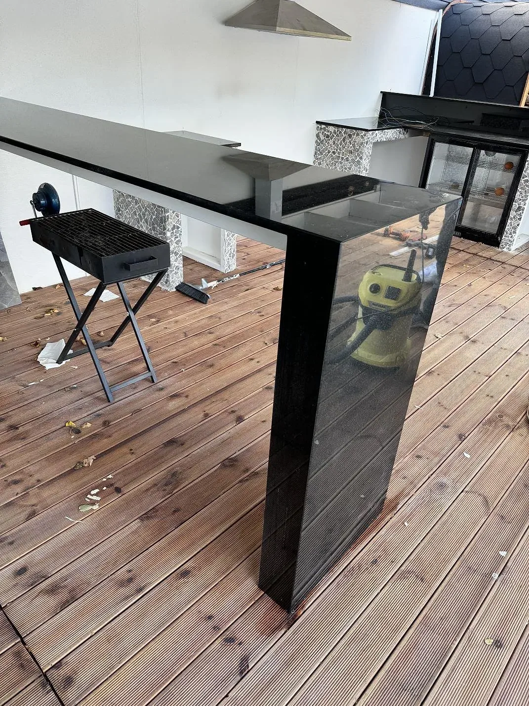 Køkkenbordplade i 20 mm poleret Nero Assoluto granit som lang arbetsyta på träterrass med fristående grill i Bara.