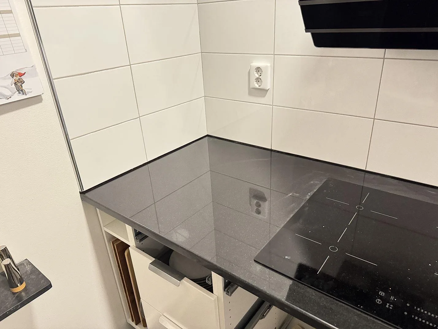 Køkkenbordplade i sort granit Nero Assoluto, 30 mm poleret, med kogeplade og blank hörnyta i ett køkken i Karlskrona.