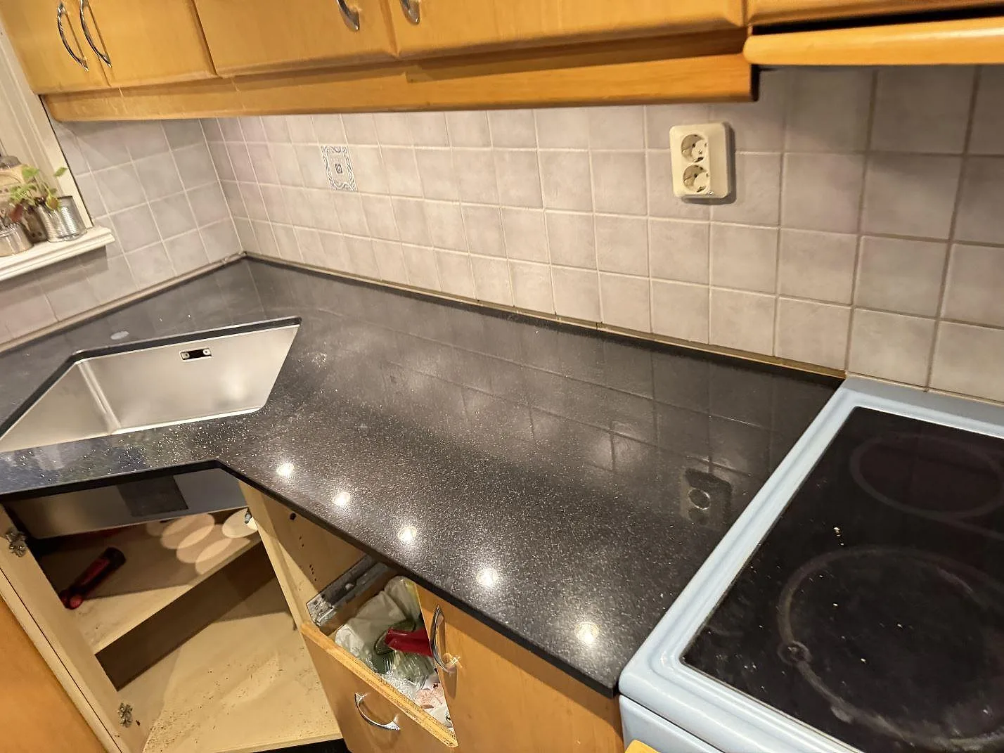 Køkkenbordplade i sort poleret Nero Assoluto granit med vask og komfur i ett køkken i Linneryd.