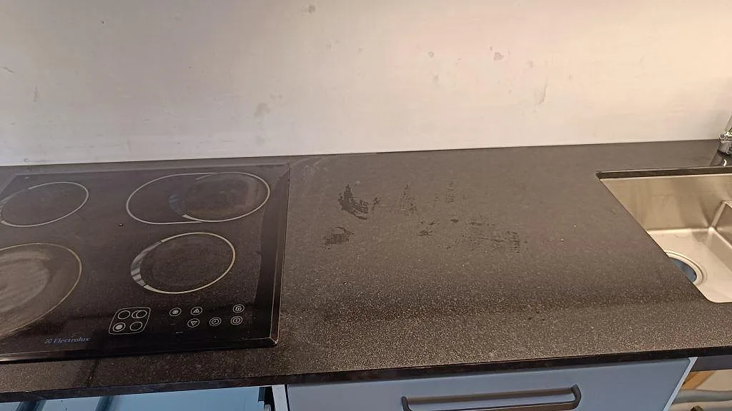 Køkkenbordplade i poleret 20 mm Nero Assoluto granit med kogeplade og rostfri vask i ett køkken i Lomma.