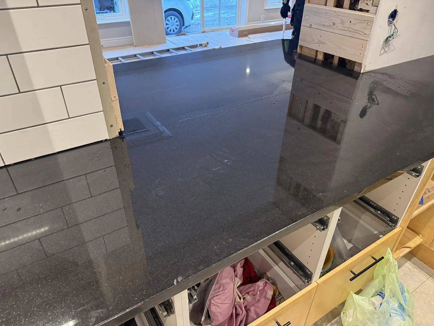 Køkkenbordplade i poleret sort Nero Assoluto-granit, 30 mm, med blank overflade og öppna skåpstommar under montering i Målilla.