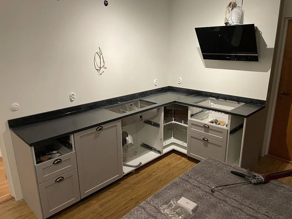 U-format køkken med køkkenbordplade i sort Nero Assoluto-granit, mat overflade og låg stänkkant under montering i Örebro.