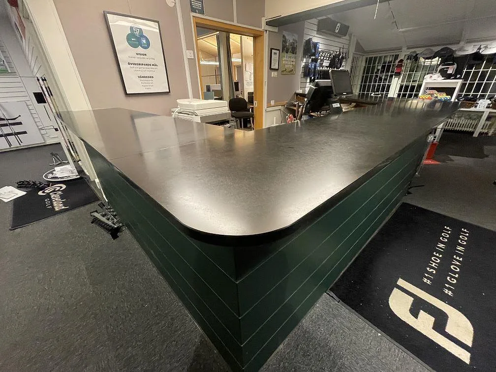 Bordplade i sort Nero Assoluto-granit med mat overflade på en stor L-formad butiksdisk i Skå.