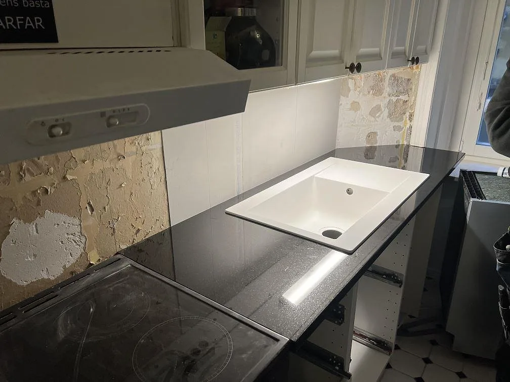 Poleret køkkenbordplade i sort granit, Nero Assoluto, monteret längs væggen i ett køkken i Stockholm.