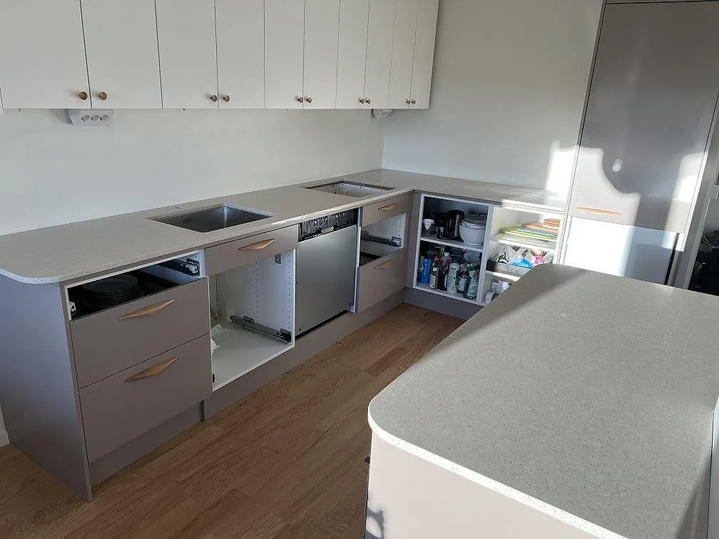 Køkkenbordplade i lys, poleret Silestone Blanco City komposit med udskæring for vask og kogeplade i ett køkken i Stockholm.