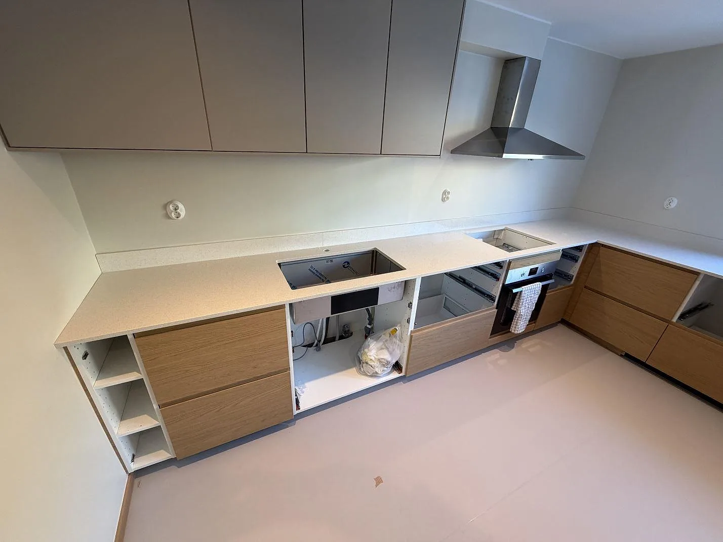 Køkkenbordplade i krämvit Silestone Blanco Maple 14, poleret, med underlimmad vask og udskæring for kogeplade i ett L-format køkken under montering i Hässelby.