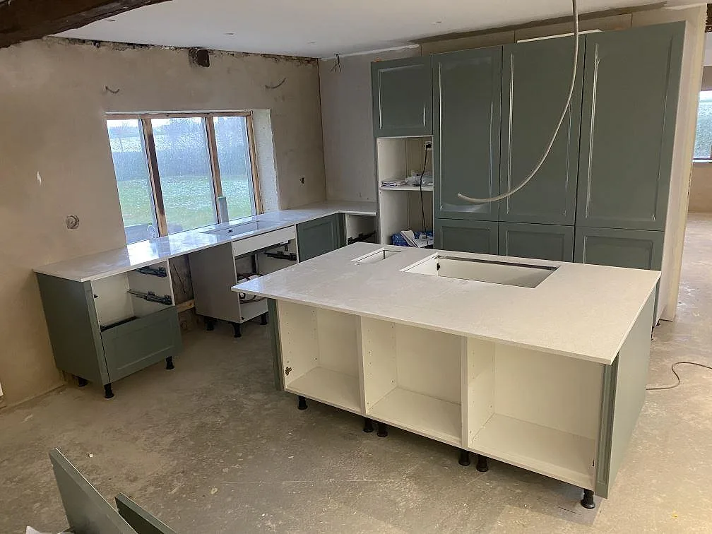 Køkkenbordplade i poleret Silestone Blanco Maple 14 med køkkenø og perimeterbänk under montering i ett køkken i Klagshamn.