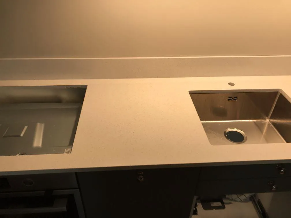 Køkkenbordplade i lys Silestone Blanco Maple, poleret, med underlimmad rostfri vask og udskæring for opvaskemaskine i ett køkken i Malmö.