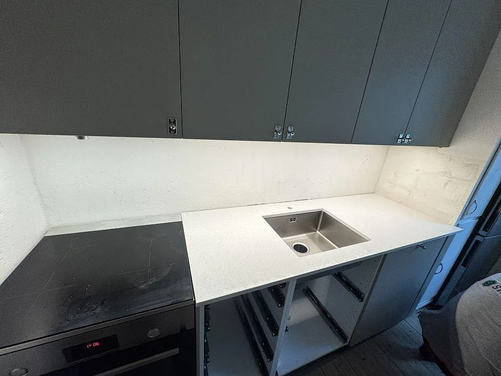 Køkkenbordplade i lys Silestone Blanco Maple 14, poleret kvartskomposit, med rostfri vask i ett køkken under montering i Malmö.