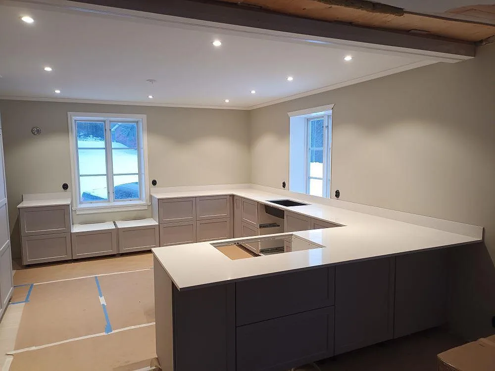 Køkkenbordplade i lys Silestone Blanco Maple, poleret, i ett U-format køkken i Toftbyn med underlimmad vask på bakre bordpladen og urtagning for kogeplade i köksön.