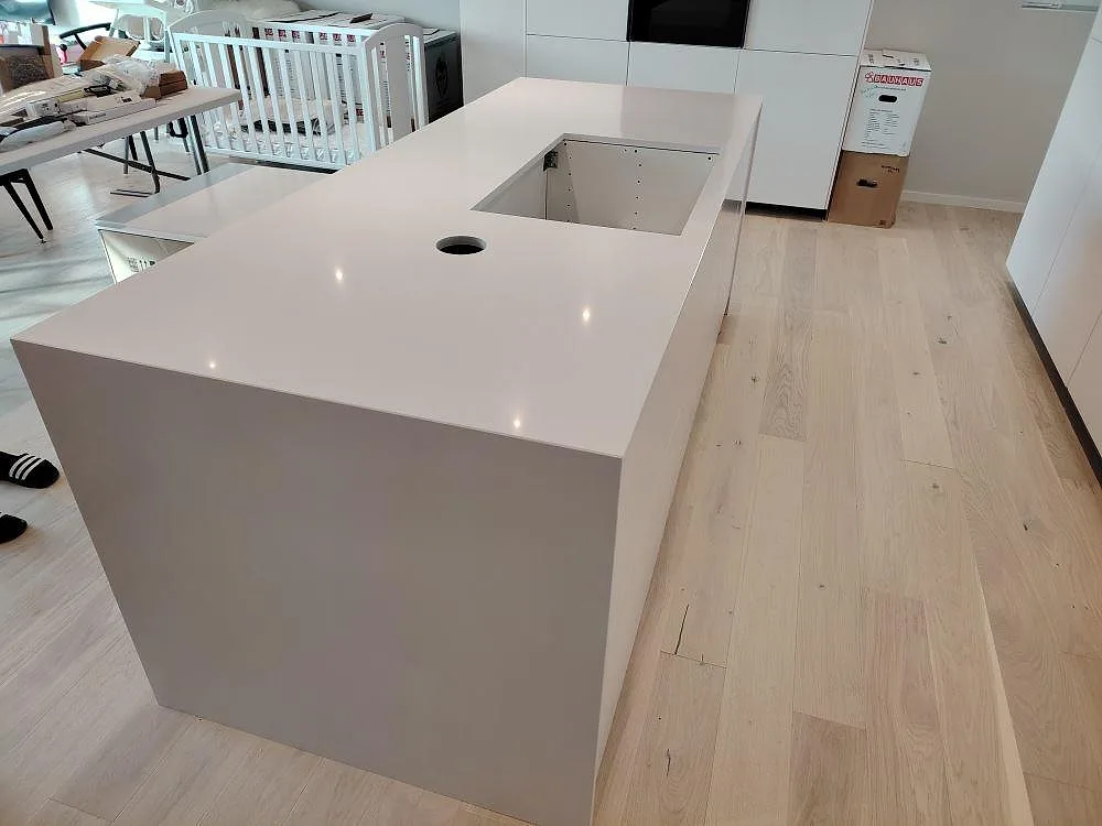 Poleret køkkenø i Silestone Blanco Zeus med udskæring for vask og armatur i ett ljust køkken under montering i Västerås.