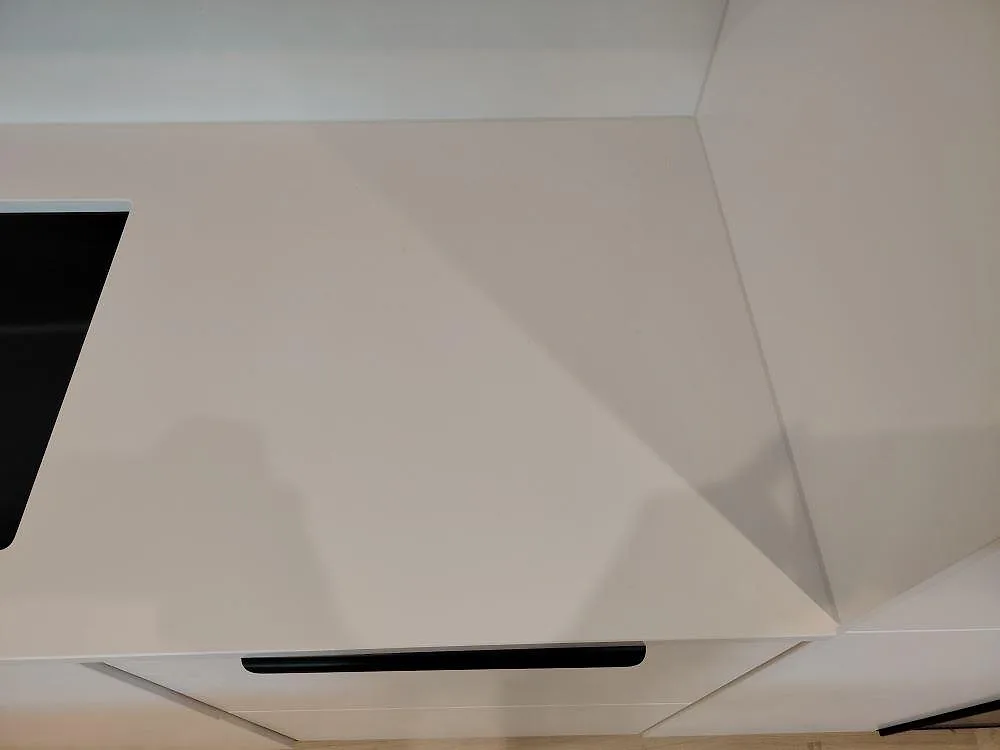 Närbild på poleret Silestone Blanco Zeus Bordplade med vitt stænkplade og sort hällkant i ett køkken i Västerås.