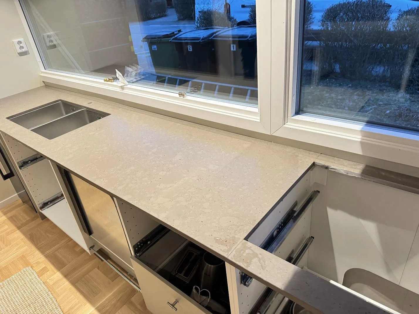 Køkkenbordplade i Silestone Brass relish, mat Mocka-overflade, med rostfri vask og öppna skabe under montering i Bjärred.